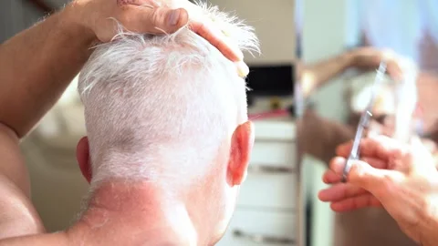 Back view white hair man doing self haircut with scissors and looks in the Stock Footage 247275934