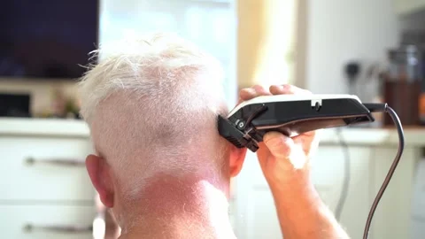 Back view white, silver hair man doing self haircut with a clipper and looks in Stock Footage 247275656