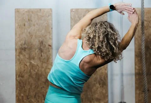 Back view of woman doing side stretch at gym Stock Photos