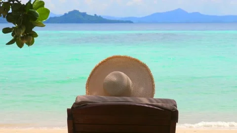 Back view of woman in hat lying on beach chair at tropical resort Video stock 234606474