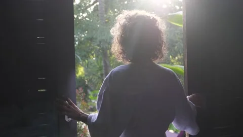 Back view of woman opening a window and stretching. Sunny morning in Bali Video stock 152052438
