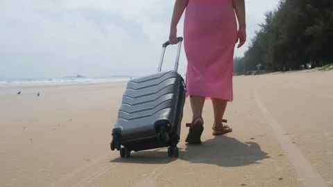 Back view woman pulling suitcase along the beach Vídeos de archivo 333098099