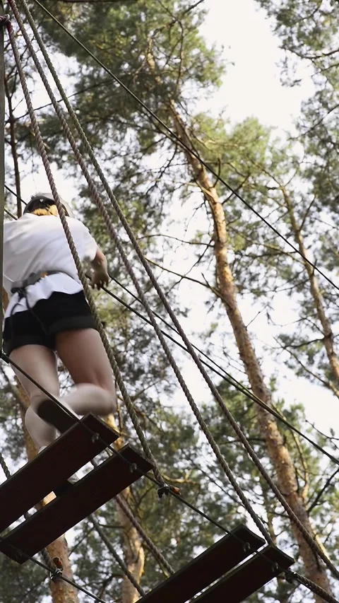 Back view of a woman quickly passing a high ropes obstacle stage Stock Footage 342782375
