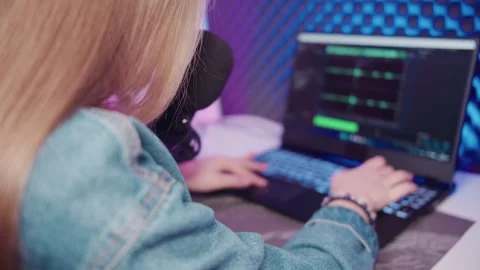 Back view of a woman sits in front of a laptop and works in a recording program Stockbeeldmateriaal 309798997