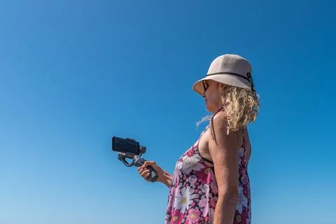 Back view of a woman using a mobile attached with a tripod outdoors with the Stock Photos