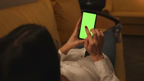 Back view. Woman using phone green mock-up screen chromakey lying on sofa couch Stock Footage 147597959