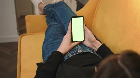 Back view. Woman using phone green mock-up screen chromakey lying on sofa couch Video stock 147943151
