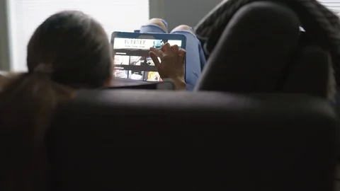 Back view of woman using tablet and lying on couch in home living room. Stock Footage 104855073