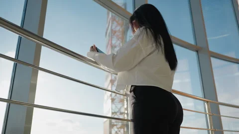 Back View Of Woman Using Tablet Near Window With Urban Background Video stock 310138876