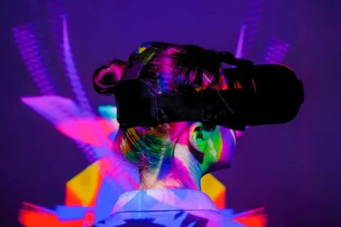 Back view: woman using virtual reality headset at dark interactive VR exhibition Foto stock