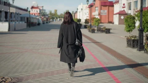Back view of woman walking on paved urban street during sunny day Vídeos de archivo 300373394