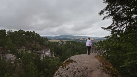 Back view of a woman in a white jacket walking on a rock, enjoying the scen.. Stock Footage 340457357