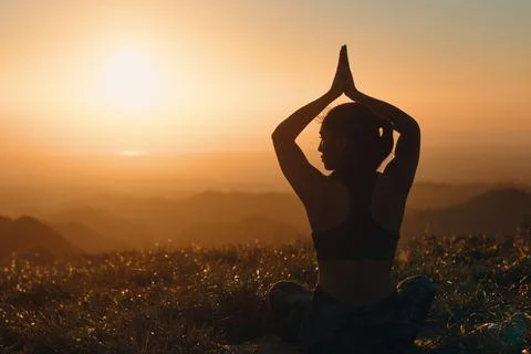 Back view of woman's silhouette that practices yoga in nature. Lotus pose wit Stock Photos