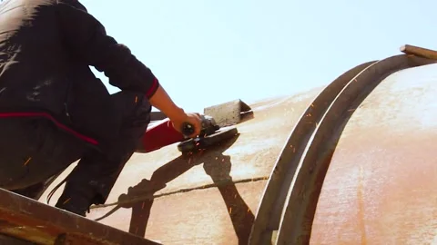 Back view of worker striking metal tank with hammer under bright sunlight Stock Footage 312423673