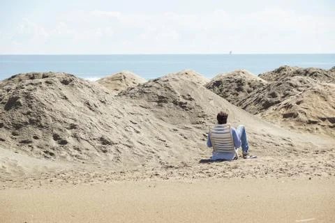 Back view of a y man reading a book on the beach Foto stock