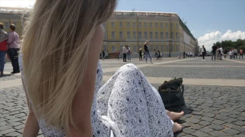 Back view of yong beautiful blond woman in white dress sitting on Palace square Stock Footage 92293133
