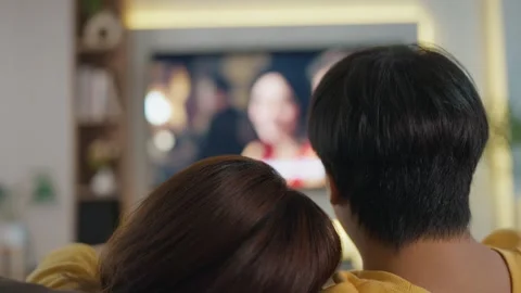 Back view young Asian couple watching movie on TV at home while sitting on sofa. Stock-Footage 251521412