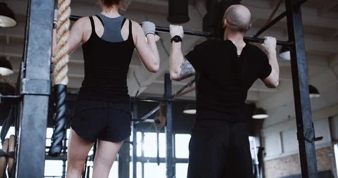 Back view young athletic Caucasian man and woman working out doing pull-ups slow Stock Footage 116923006