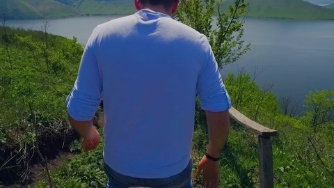 Back view of young bearded man in casual outfit excitedly walking down the pass Stock-Footage 108727424