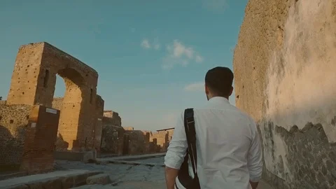 Back view of young bearded man in stylish wear walking with backpack down the Stock Footage 108730285