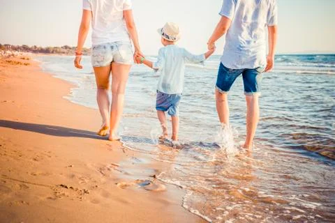 Back view of young blonde family walking on beach Stock Photos