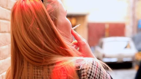Back view of young blonde stylish woman smoking cigarette outside on city street 스톡 동영상 117695533
