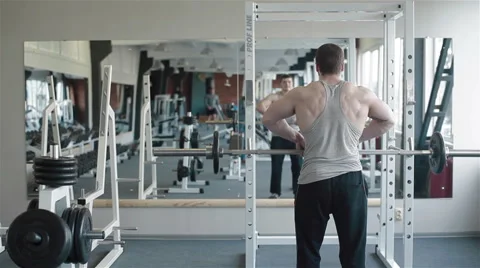 Back view of a young bodybuilder lifting weight in front of the mirror Stock Footage 49162346