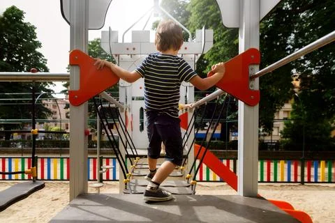 Back view of a young boy carefully crossing a suspended rope bridge Stock Photos