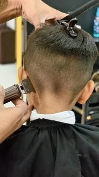 Back view of a young boy getting a professional haircut at a barbershop Stock Photos