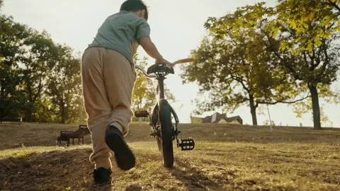 Back view of a young boy holding on to his bike in the park. Children health 스톡 동영상 253979230