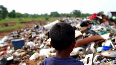 Back View: Young Boy Standing by a Pile of Trash in Rural Area Stockbeeldmateriaal 283871443