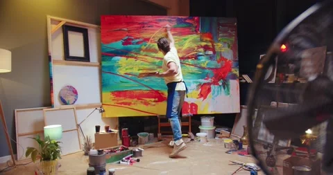 Back view of young Caucasian man painter emotionally drawing on big canvas using Stock Footage 149584195