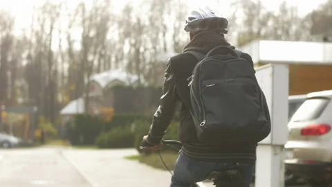 Back view of young commuter with a backpack riding to work by bike Stock Footage 133299380