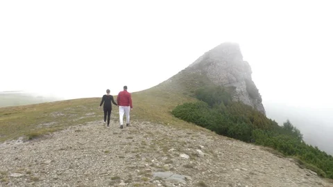 Back view of young couple holding their hands enjoying their walk on mountain Stock Footage 86218389