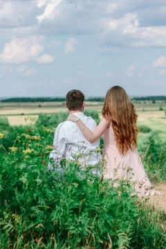 Back view of young couple sitting at the hill and looking to the valley Stock Photos