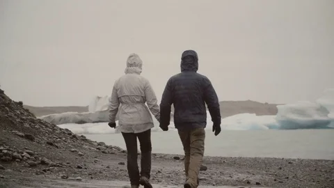 Back view of young couple walking in ice lagoon in Iceland. Man and woman Stock Footage 82952336