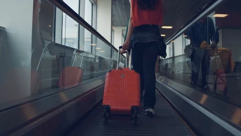 Back view of a young couple walking in the airport terminal while carrying red Stock Footage 108869022