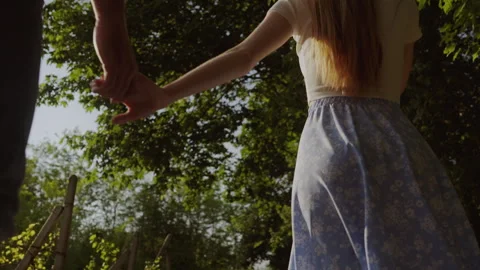 Back view of a young couple walking through rape field in sunny day, woman Stock Footage 252172240