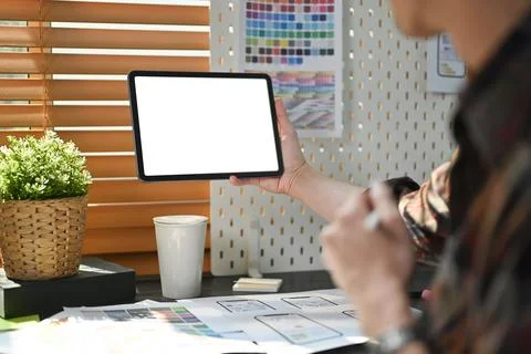 Back view of young creative man sitting at workplace and using digital tablet Stockfoto's