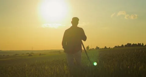 Back view of the young farmer standing at the field with shovel and looking at Stock Footage 157645540
