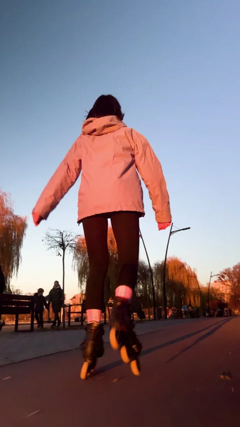 Back view of young female rollerblader enjoys evening ride in urban park Stock Footage 346542106