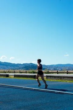 Back view of a young female sprinter running on an athletics track Stock Photos
