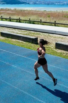 Back view of a young female sprinter running on an athletics track Stock Photos