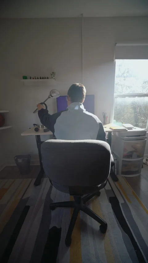 Back view of a young freelancer sitting at his desk and putting on headphones Video stock 344163605