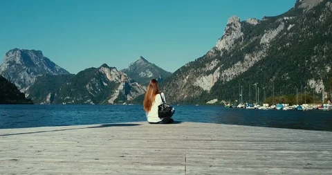 Back view of young girl with long hair and backpack sitting at the edge Vidéo 122517088