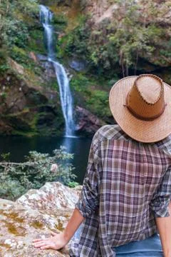 Back view of young girl in straw hat and looking at waterfall. Caucasian young Stock Photos