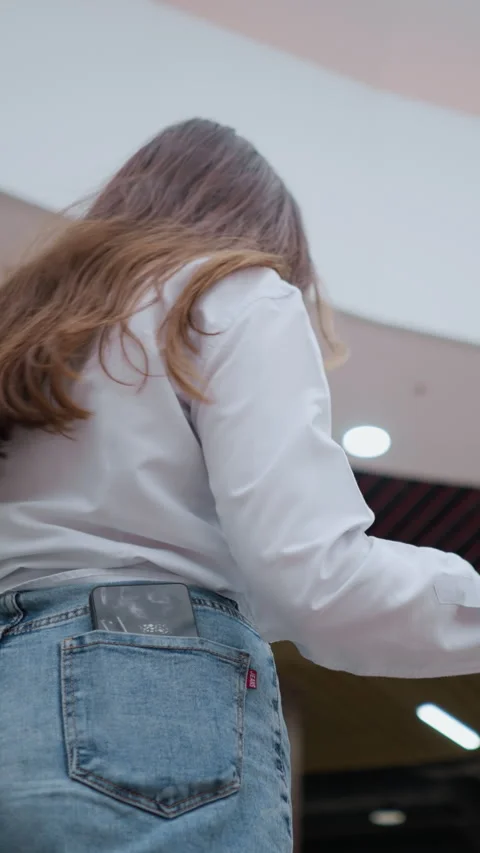 Back View of Young Lady on Moving Escalator Looking Around in Modern Mall Stock Footage 318839828