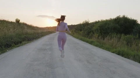 Back view of young lady that running on the road Stock Footage 157969641