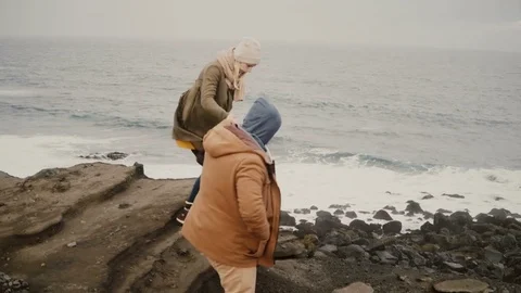 Back view of young man and woman standing on the shore of the sea in cold day Stock Footage 82973600