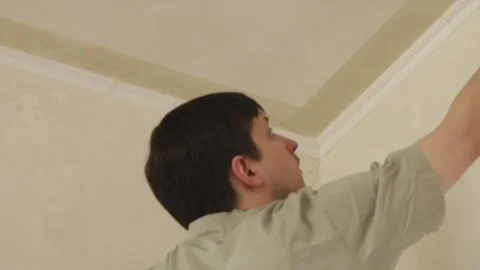 Back view of young man applying anti mold primer to ceiling corner Stock Footage 340404928
